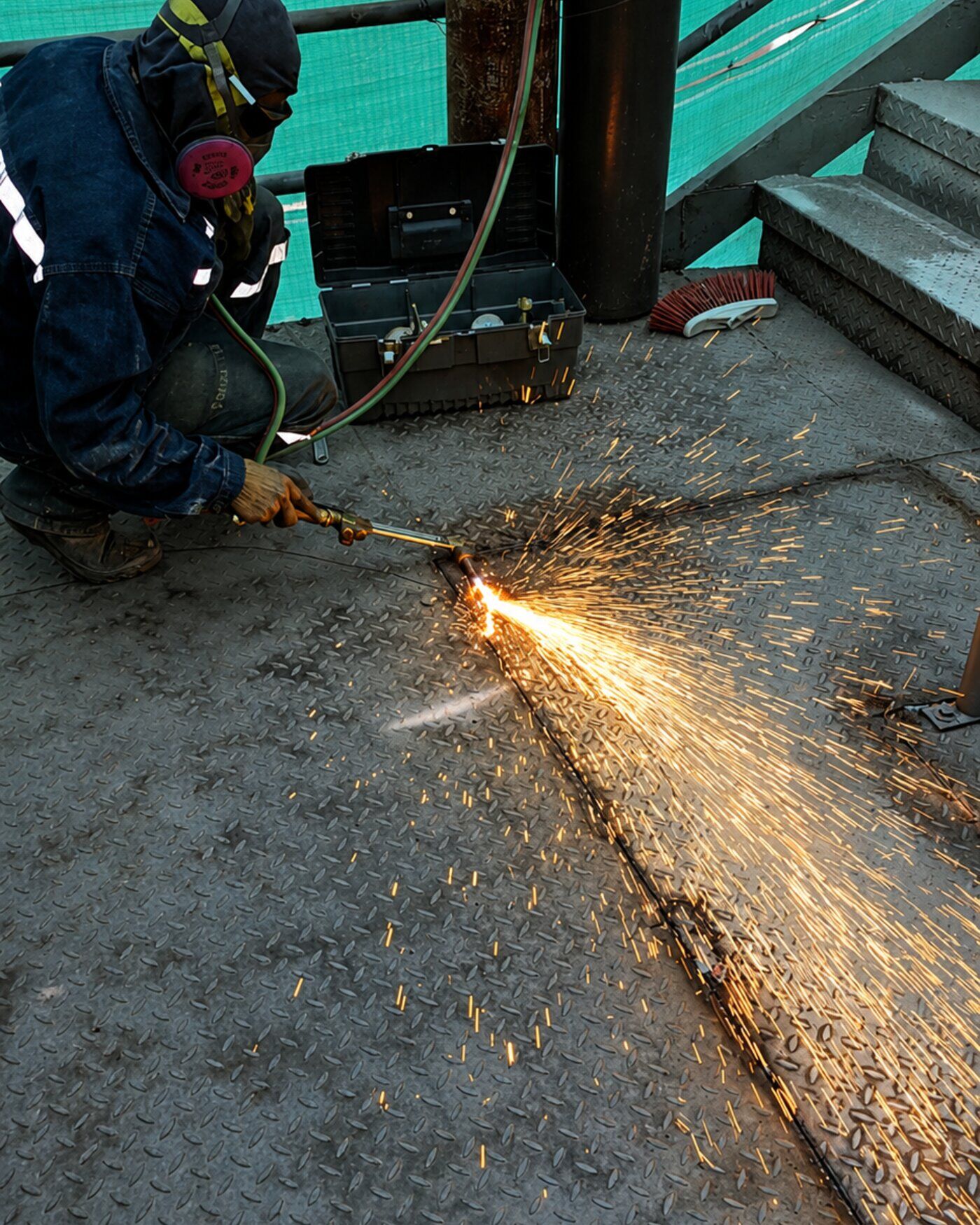 Soldador certificado de 3C ejecutando corte por oxicombustión sobre estructura metálica con chispas — metalmecánica bajo norma AWS D1.1
